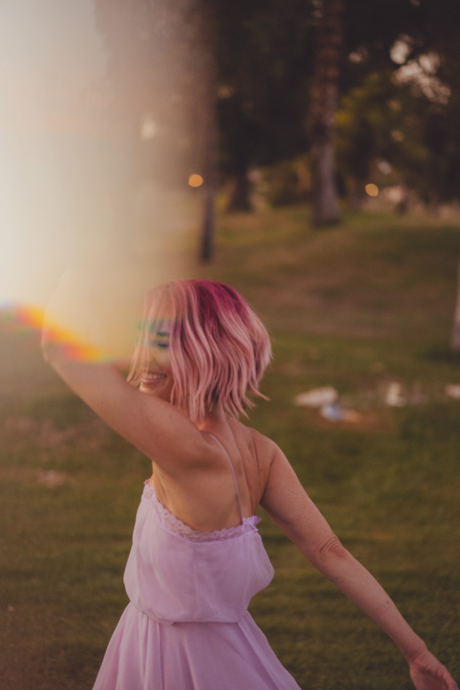 Bri turning in the sunlight in her lavender dress, with a soft rainbow of light across the photograph.